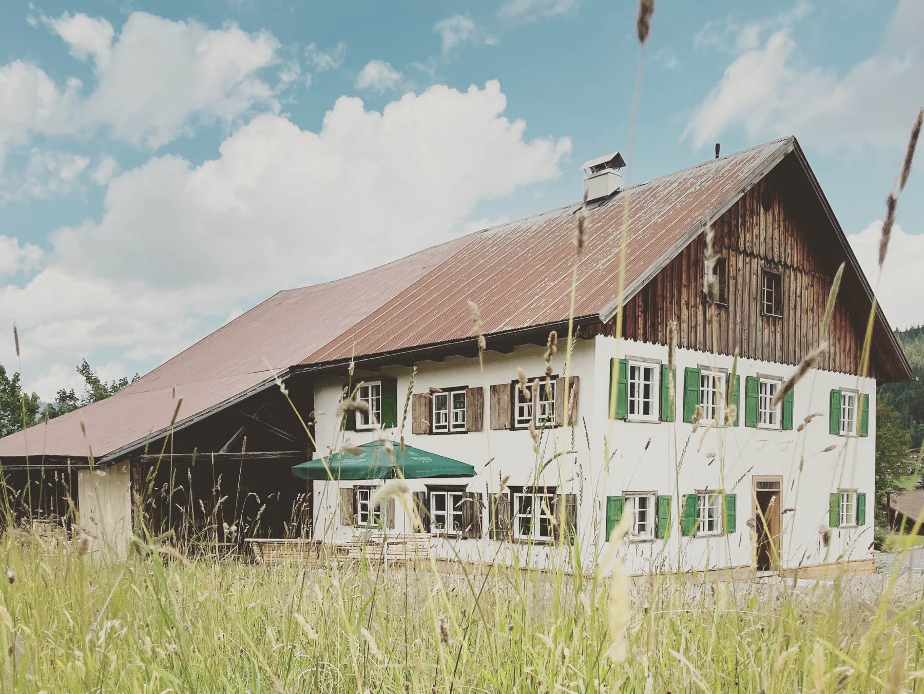 Restauriertes Bauernhaus in Schattwald mit grünen Fensterläden auf einer Wiese